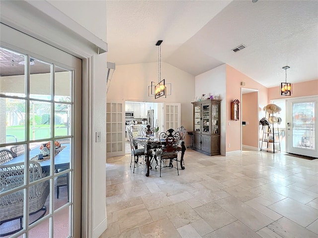 dining room featuring a chandelier, a textured ceiling, and lofted ceiling