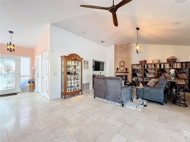 living room with high vaulted ceiling, a textured ceiling, ceiling fan with notable chandelier, and a fireplace