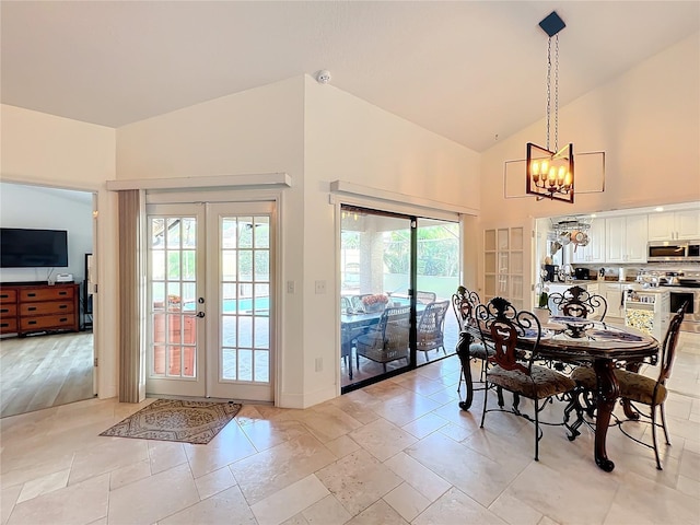 dining space with french doors, a notable chandelier, light wood-type flooring, and high vaulted ceiling