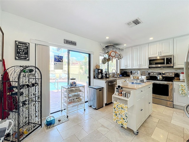 kitchen with a kitchen island, appliances with stainless steel finishes, sink, and white cabinets