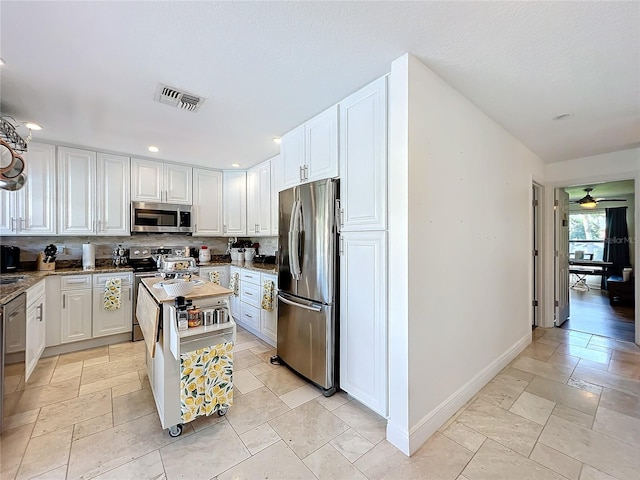 kitchen featuring white cabinets, stainless steel appliances, a center island, and tasteful backsplash