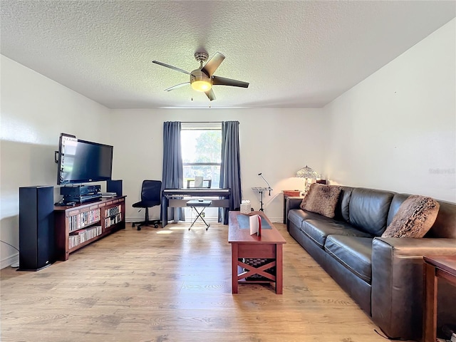 living room with light hardwood / wood-style floors, ceiling fan, and a textured ceiling