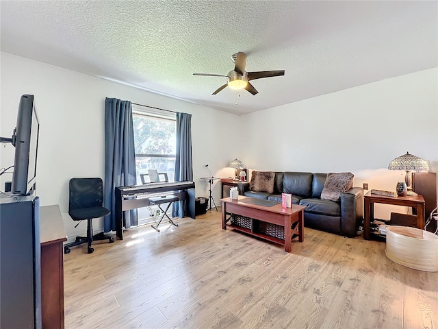 living room featuring ceiling fan, a textured ceiling, and light wood-type flooring