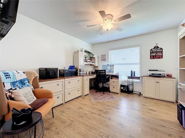 office space featuring ceiling fan, a textured ceiling, built in desk, and light hardwood / wood-style floors