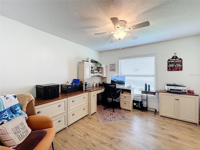 office area featuring ceiling fan, a textured ceiling, built in desk, and light hardwood / wood-style floors