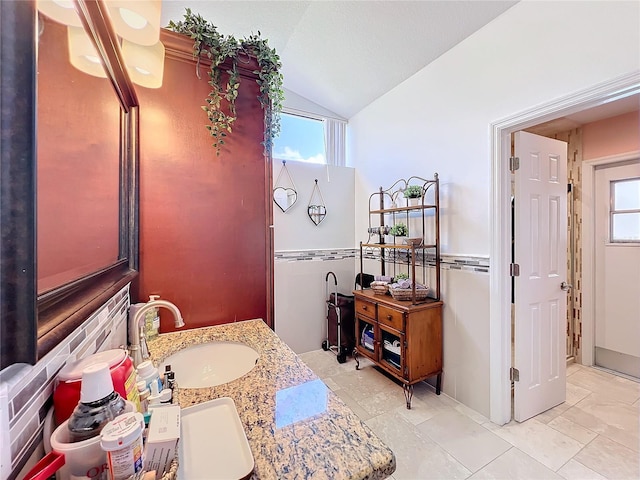 bathroom with vanity, a wealth of natural light, and vaulted ceiling