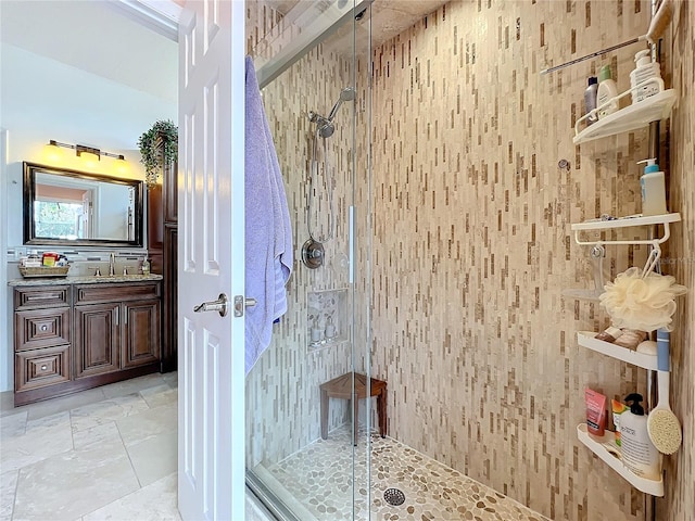 bathroom featuring a shower with shower door and vanity