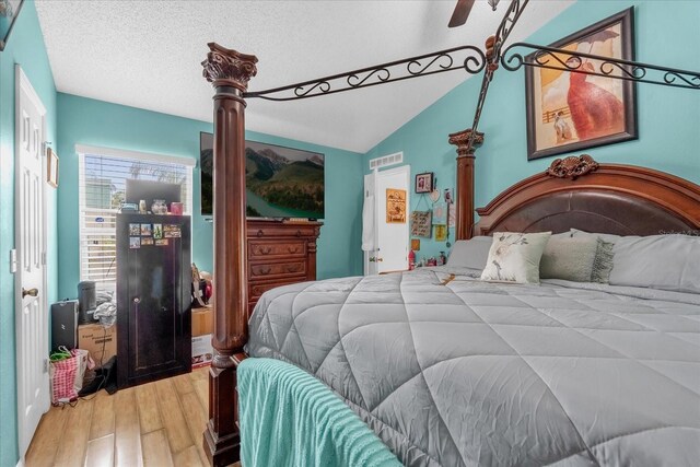 bedroom with hardwood / wood-style flooring, ceiling fan, lofted ceiling, and a textured ceiling