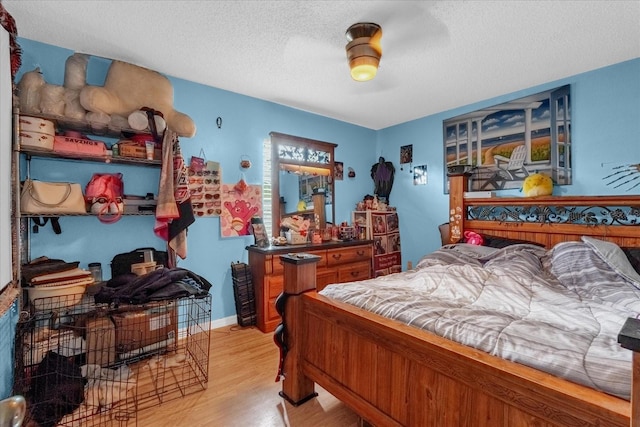 bedroom featuring ceiling fan, light hardwood / wood-style floors, and a textured ceiling