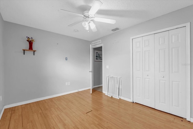 unfurnished bedroom featuring ceiling fan, hardwood / wood-style flooring, a closet, and a textured ceiling