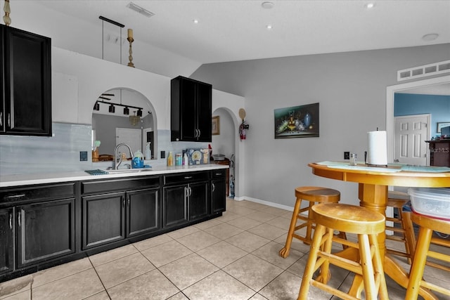 kitchen featuring vaulted ceiling, sink, and light tile patterned floors