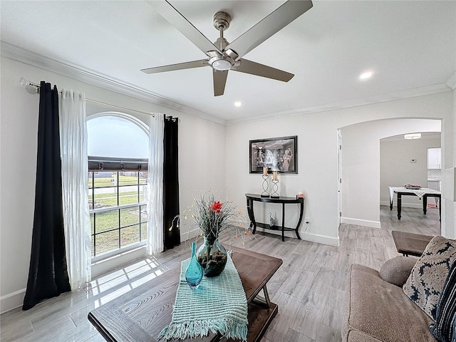 living room with light hardwood / wood-style floors, ornamental molding, and ceiling fan