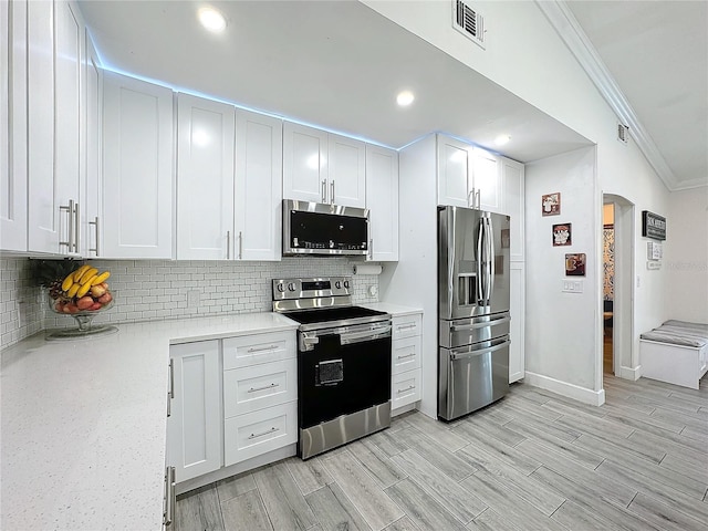 kitchen featuring tasteful backsplash, white cabinetry, light hardwood / wood-style flooring, ornamental molding, and stainless steel appliances