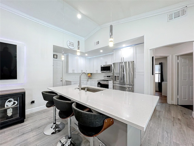 kitchen with sink, hanging light fixtures, stainless steel appliances, white cabinets, and high vaulted ceiling