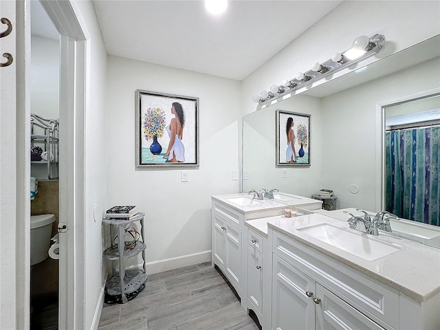 bathroom with toilet, hardwood / wood-style floors, and vanity