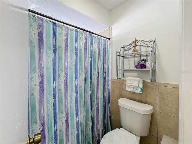 bathroom with toilet, tile walls, and a shower with shower curtain