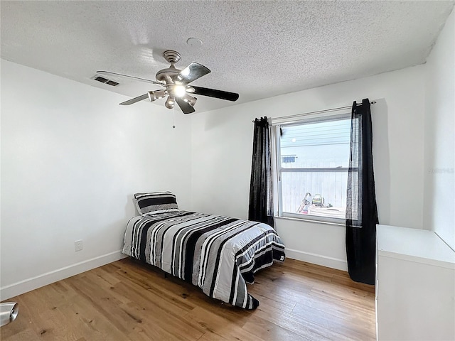 bedroom with hardwood / wood-style floors, a textured ceiling, and ceiling fan