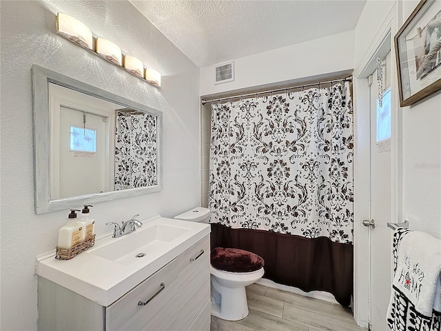 bathroom with vanity, toilet, a textured ceiling, and plenty of natural light