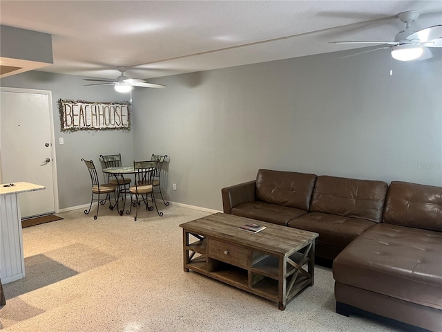 living area featuring baseboards and a ceiling fan