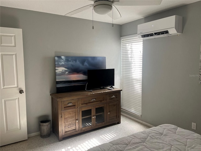 bedroom with ceiling fan, an AC wall unit, light speckled floor, and baseboards