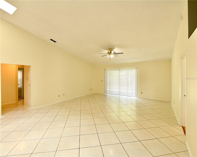 tiled spare room with high vaulted ceiling, a skylight, and ceiling fan