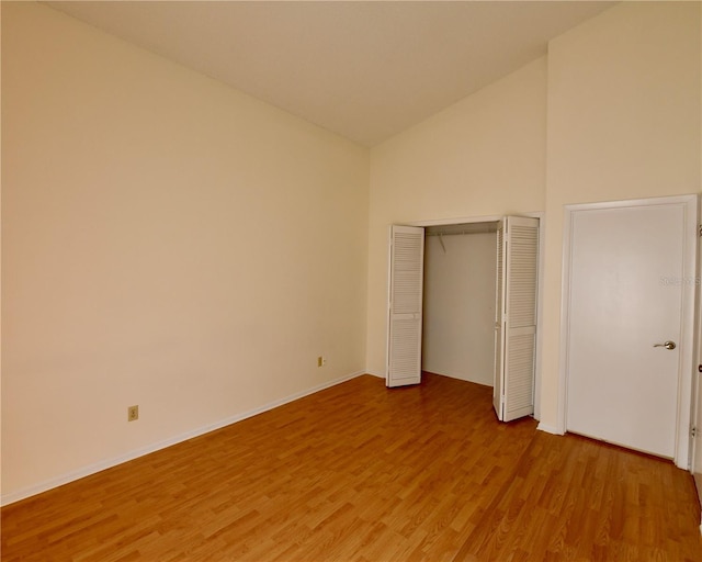 unfurnished bedroom with hardwood / wood-style floors and high vaulted ceiling