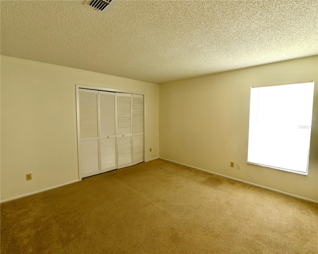 unfurnished bedroom with a closet, light carpet, and a textured ceiling