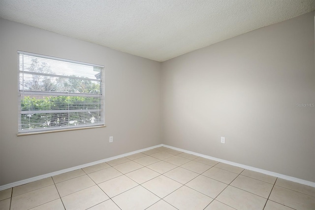 unfurnished room with a textured ceiling and light tile patterned flooring