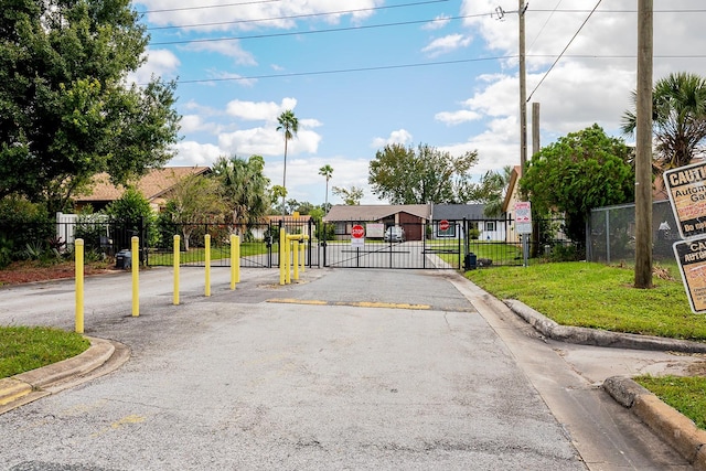 view of road with traffic signs, a gate, curbs, and a gated entry