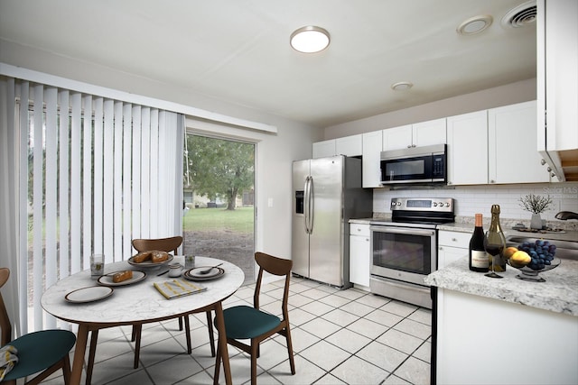 kitchen featuring light tile patterned floors, white cabinetry, stainless steel appliances, tasteful backsplash, and light stone countertops