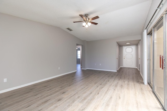 spare room with a textured ceiling, ceiling fan, light wood-style flooring, baseboards, and vaulted ceiling