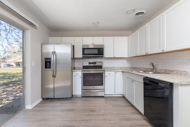 kitchen with tasteful backsplash, white cabinetry, stainless steel appliances, and a sink