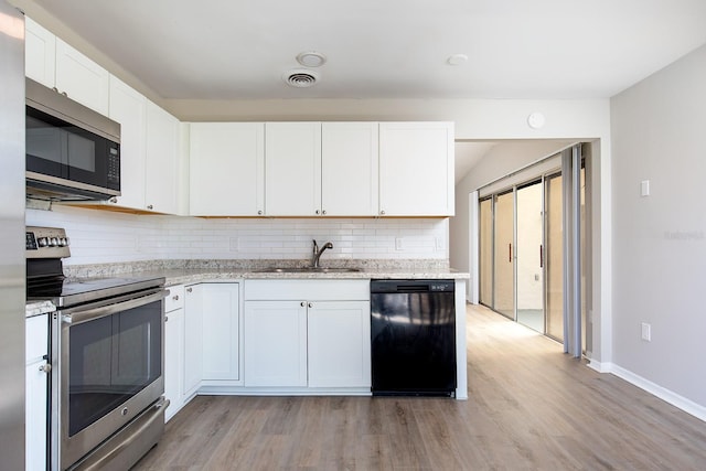 kitchen with stainless steel appliances, a sink, white cabinetry, visible vents, and decorative backsplash