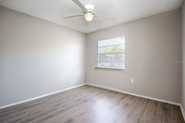 empty room with ceiling fan, a textured ceiling, wood finished floors, and baseboards