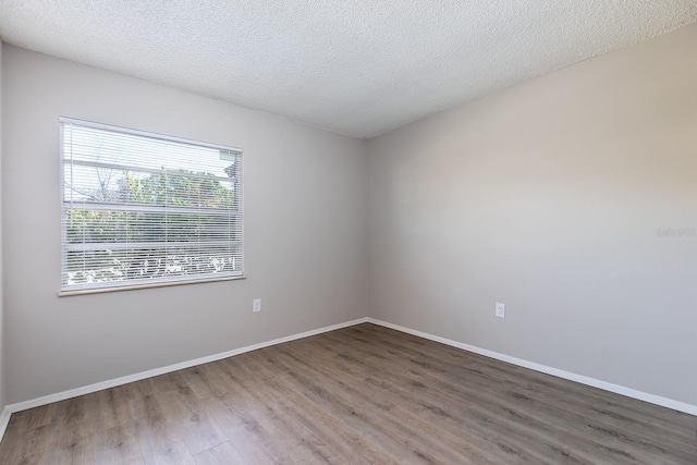 unfurnished room featuring a textured ceiling, baseboards, and wood finished floors