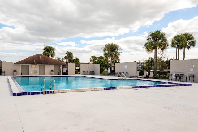 community pool with a patio area and fence