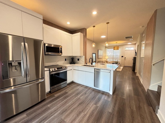 kitchen featuring sink, kitchen peninsula, white cabinetry, stainless steel appliances, and dark hardwood / wood-style floors