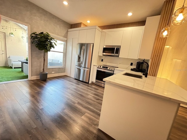 kitchen featuring appliances with stainless steel finishes, sink, hanging light fixtures, white cabinetry, and dark hardwood / wood-style floors