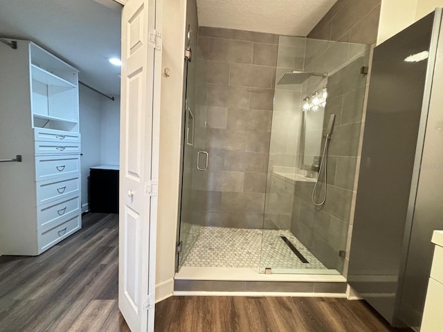 bathroom featuring an enclosed shower, a textured ceiling, and wood-type flooring