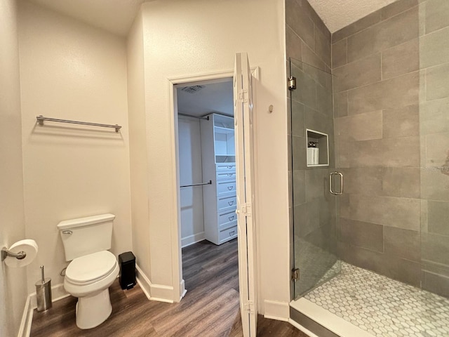 bathroom featuring toilet, a textured ceiling, walk in shower, and hardwood / wood-style flooring