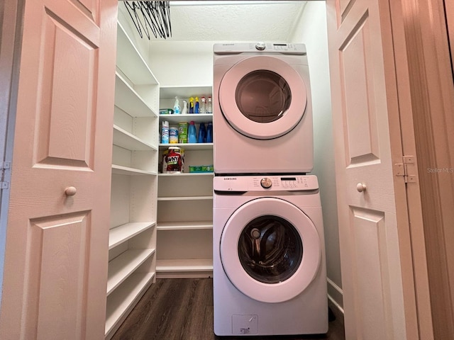 laundry area with a textured ceiling, stacked washer and clothes dryer, and dark hardwood / wood-style floors