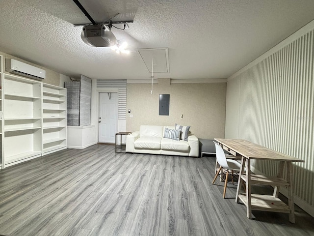 living room with a textured ceiling, a wall mounted AC, electric panel, and light wood-type flooring