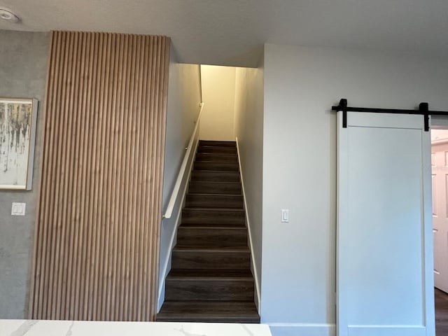 stairway with a barn door and wood-type flooring