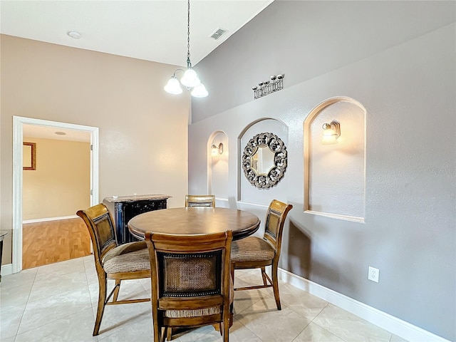 tiled dining space with an inviting chandelier and vaulted ceiling