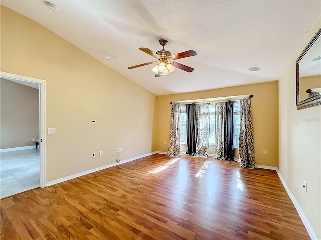 empty room featuring lofted ceiling, a textured ceiling, wood-type flooring, and ceiling fan