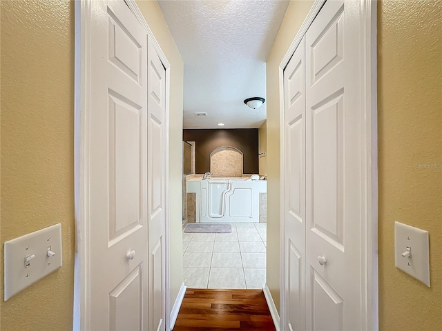 hall featuring light hardwood / wood-style flooring and a textured ceiling