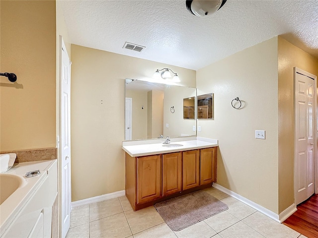 bathroom featuring vanity, a tub to relax in, a textured ceiling, and tile patterned flooring