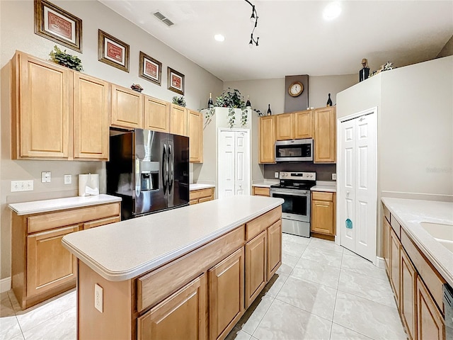 kitchen with vaulted ceiling, light tile patterned flooring, appliances with stainless steel finishes, and a center island