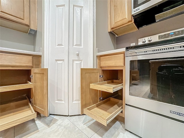 kitchen with appliances with stainless steel finishes, light tile patterned floors, and light brown cabinets