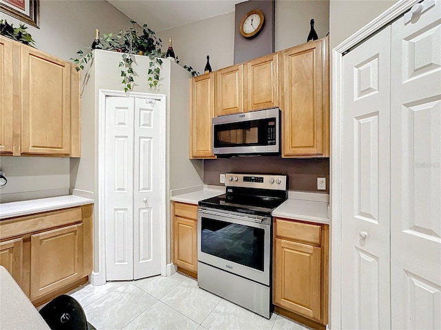 kitchen with light brown cabinetry, light tile patterned flooring, and stainless steel appliances